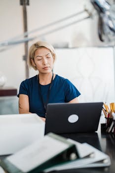 Professional woman focusing on her laptop while working in a modern office setting.