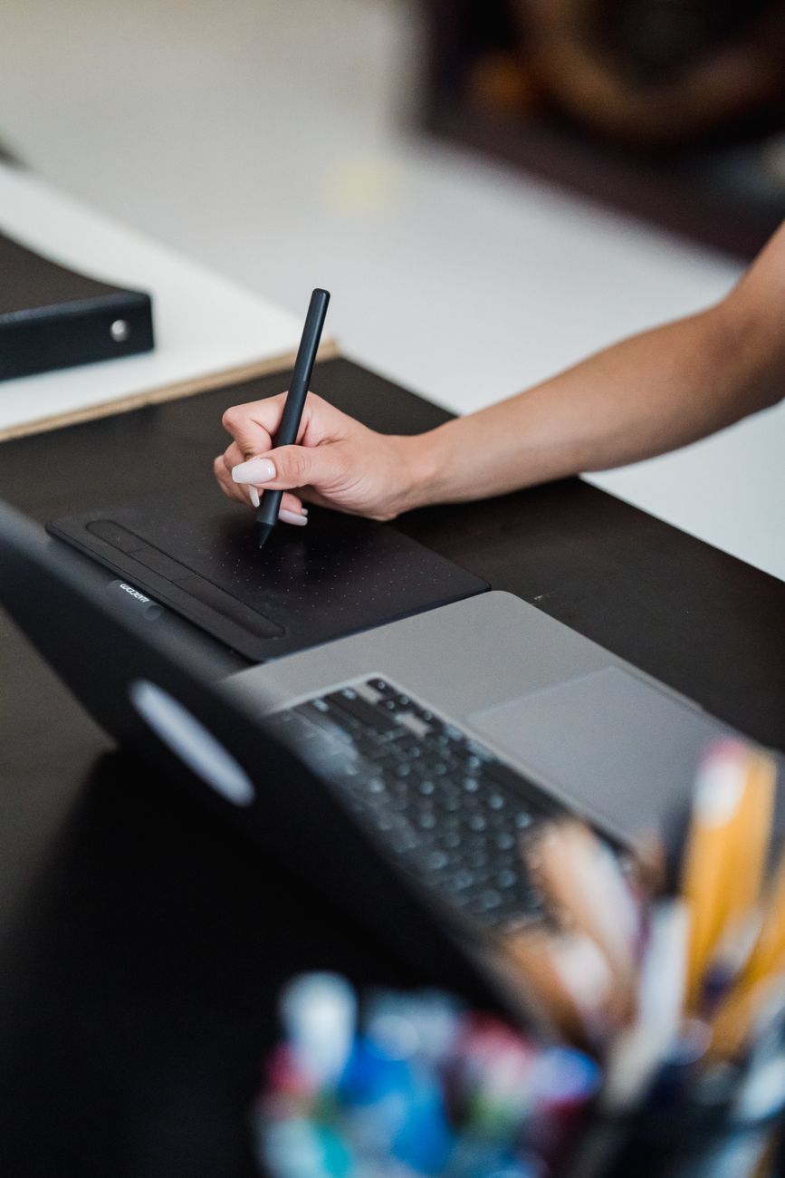 Personne utilisant une tablette graphique et un ordinateur portable dans un espace de travail créatif