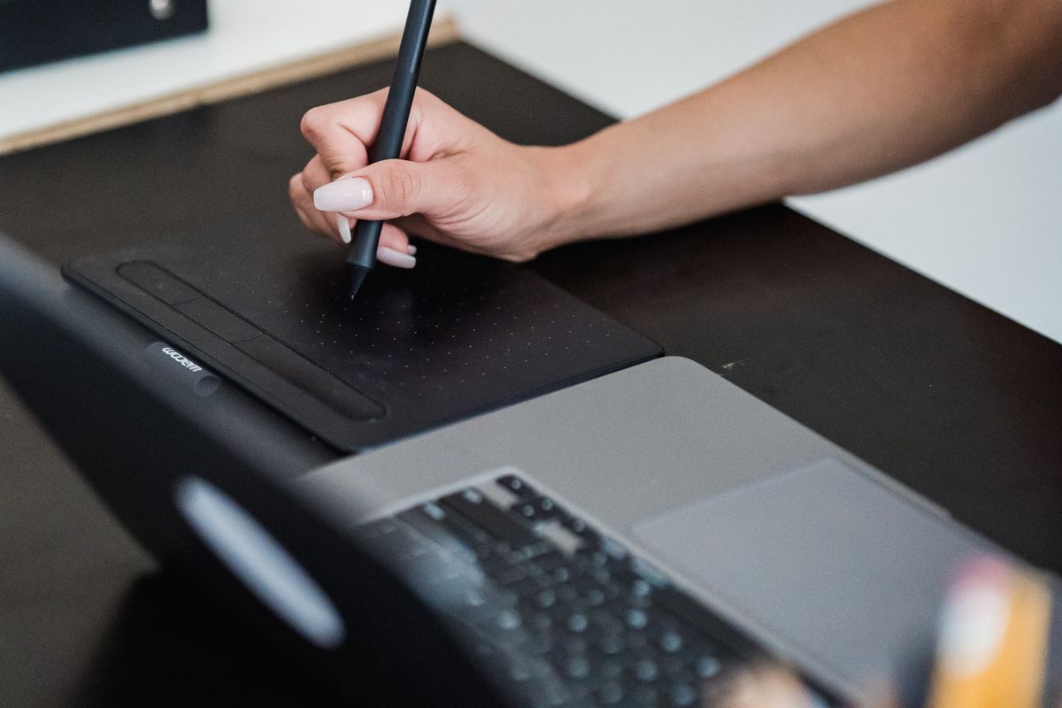 A graphic designer using a pen tablet alongside a laptop