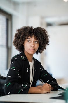 Focused businesswoman with curly hair sitting at desk in modern office space.