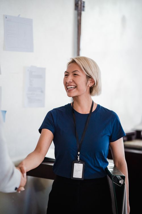 Free Friendly businesswoman in a blue shirt shaking hands during meeting, radiating professionalism and approachability. Stock Photo