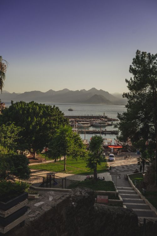 Free Beautiful harbor scene at twilight with boats, mountains, and a city park. Stock Photo