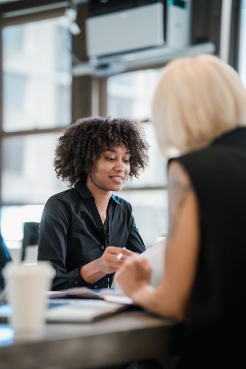 Free Two women engaging in a professional meeting in a modern office setting. Stock Photo