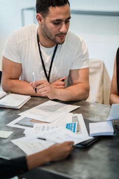 Team members engage in a strategy meeting discussing important documents around a table.