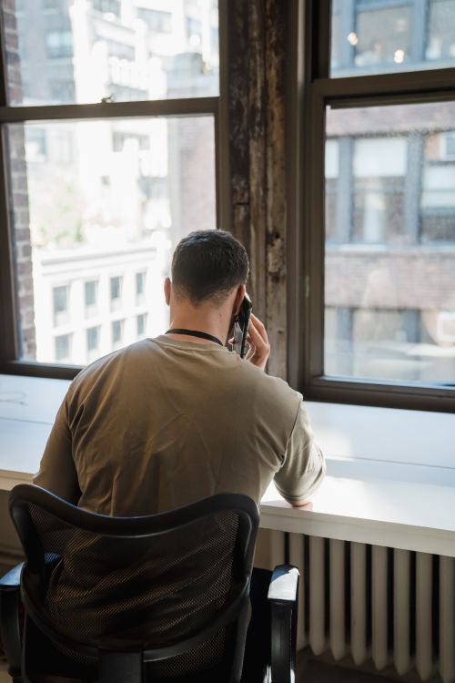 Free Businessman making call in an urban office setting overlooking cityscape. Stock Photo