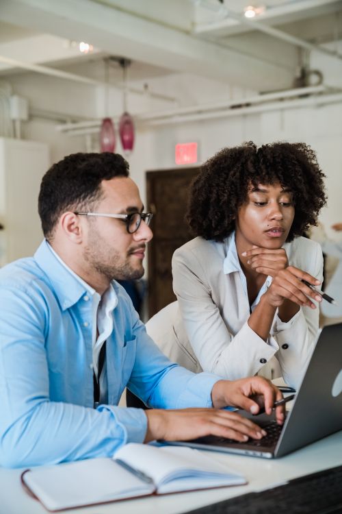 Free A man and a woman collaborating on a laptop in a modern office setting. Stock Photo