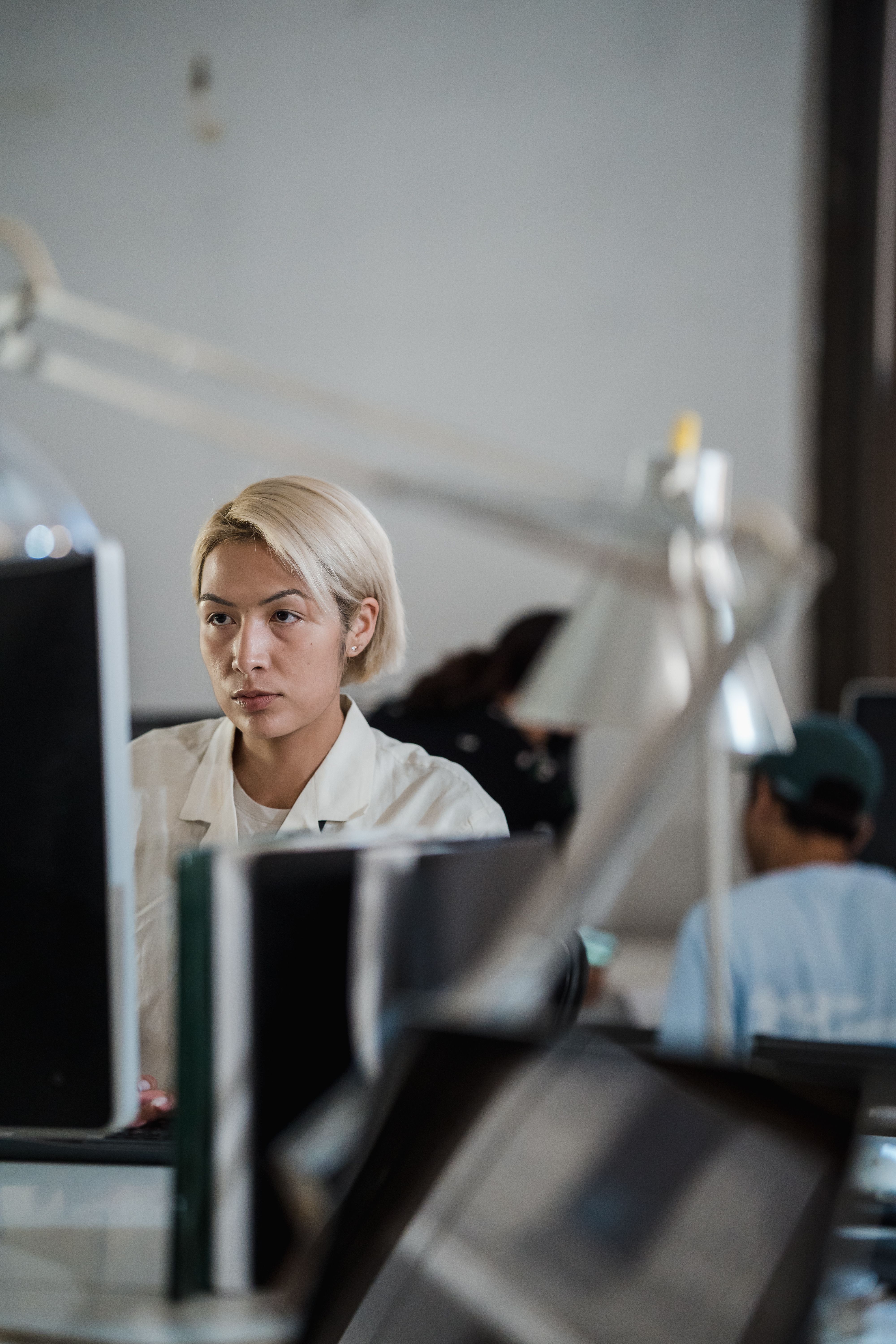 A woman intensely focused on her work at a modern office desk with computers around her.