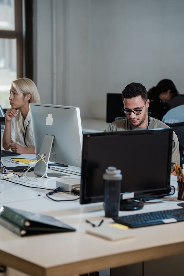 Employees Working On Computers In Office