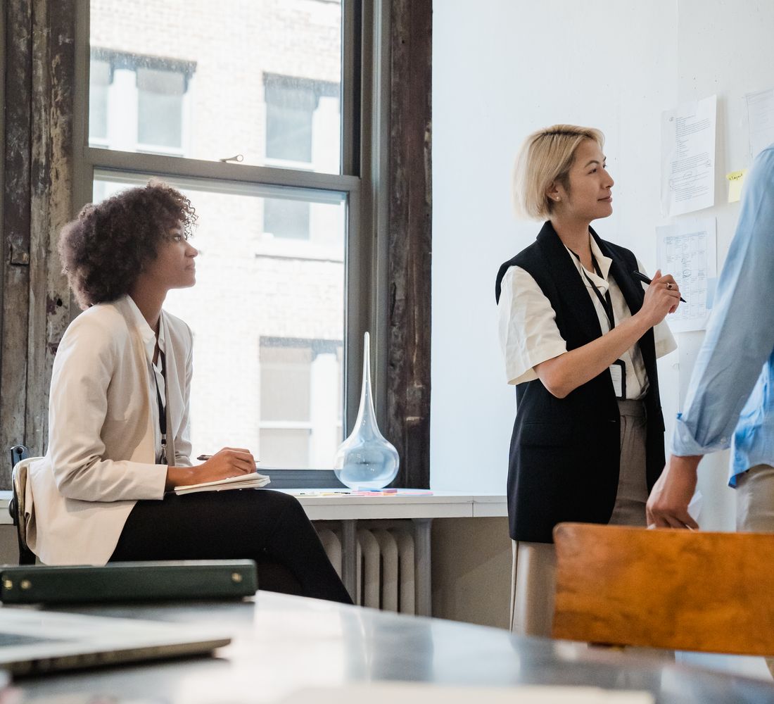 Two colleagues talking through notes on an office wall