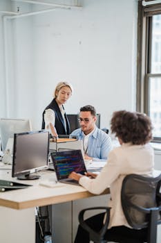 Business team working collaboratively in a modern office setting with computers and laptops.