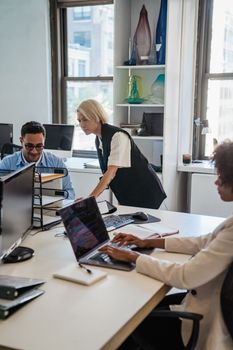 Professionals working collaboratively in a contemporary office environment with laptops and documents.