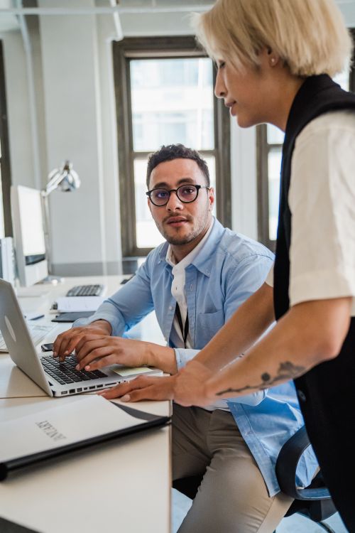 Free Two colleagues working together at a desk with a laptop, fostering professional collaboration. Stock Photo