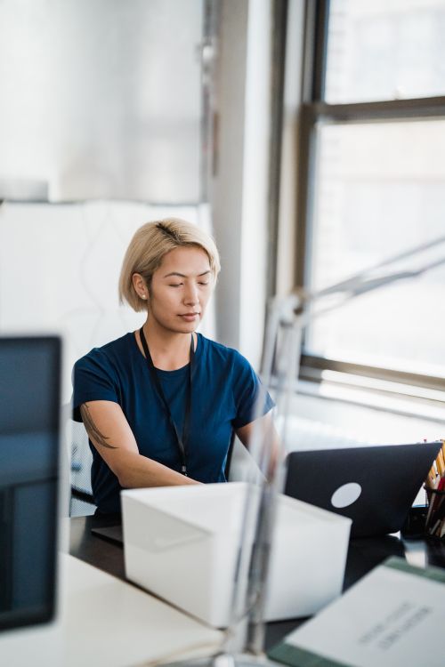 Free A determined woman concentrating on work at her desk in a modern office environment. Stock Photo