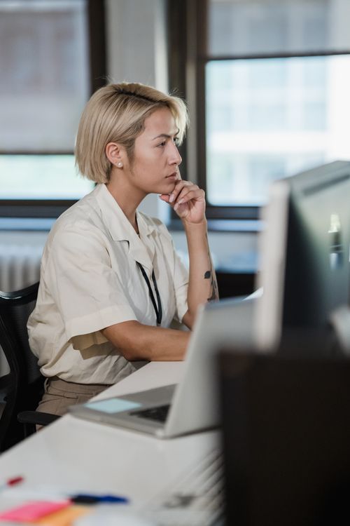 Free Woman deeply focused on work at her desk in a modern office setting. Stock Photo