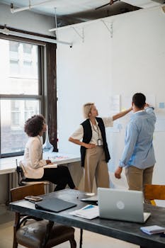 Group of professionals brainstorming ideas in a modern office using a whiteboard for effective teamwork.