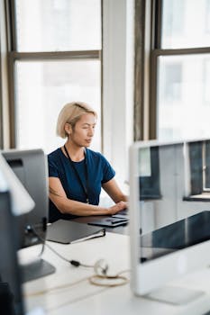 A focused woman working on a computer in a bright, modern office setting.