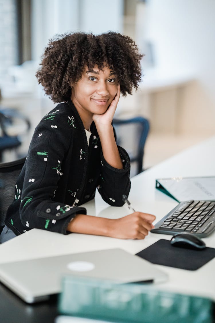 Smiling Woman Sitting At Office Desk 