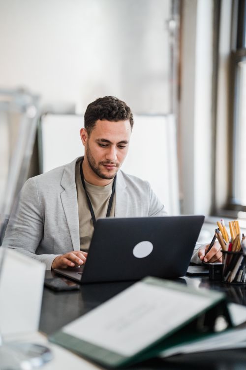 Free Focused man working on a laptop in a modern office setting, emphasizing productivity and technology. Stock Photo