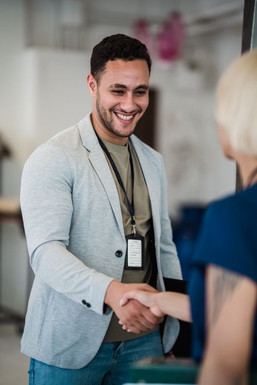 Free Smiling man and woman exchanging a handshake in a modern office environment. Stock Photo