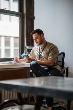 A young man focused on work while seated at a desk in a contemporary office setting.