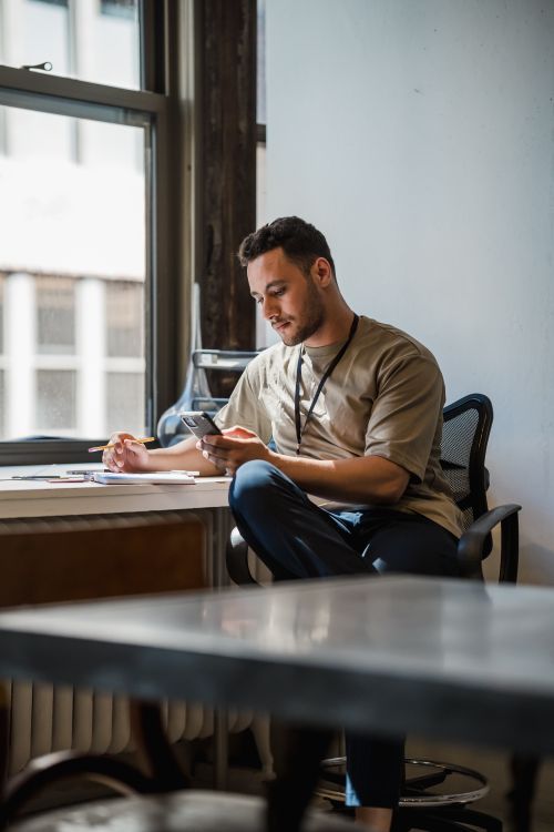 Free A young man focused on work while seated at a desk in a contemporary office setting. Stock Photo