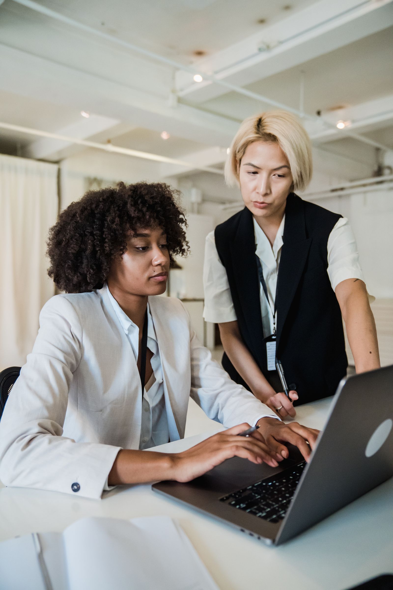 A mentor guiding an intern at a laptop in a bright, modern office