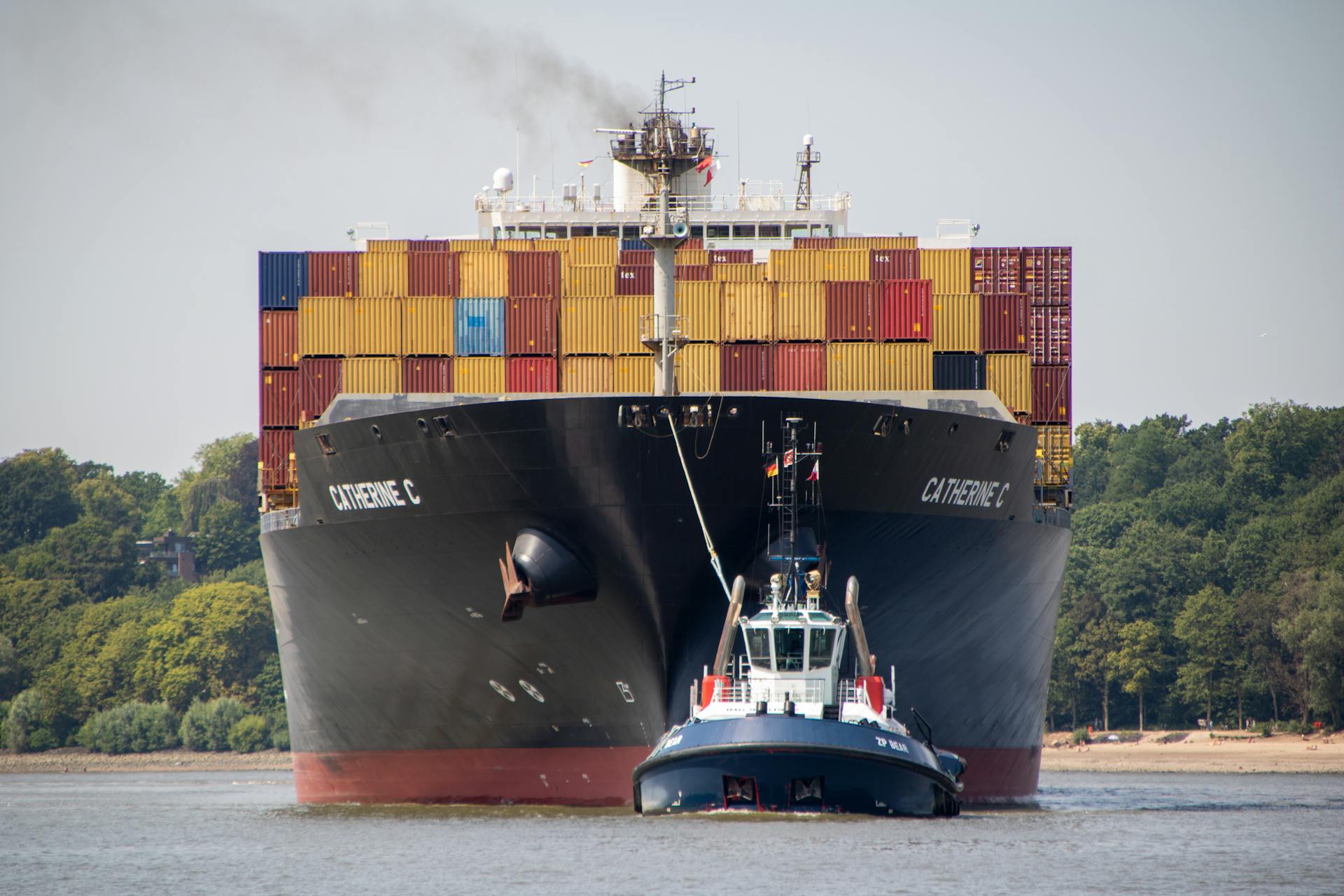 Massive container ship guided by a tugboat in Hamburg's busy port, symbolizing global trade.