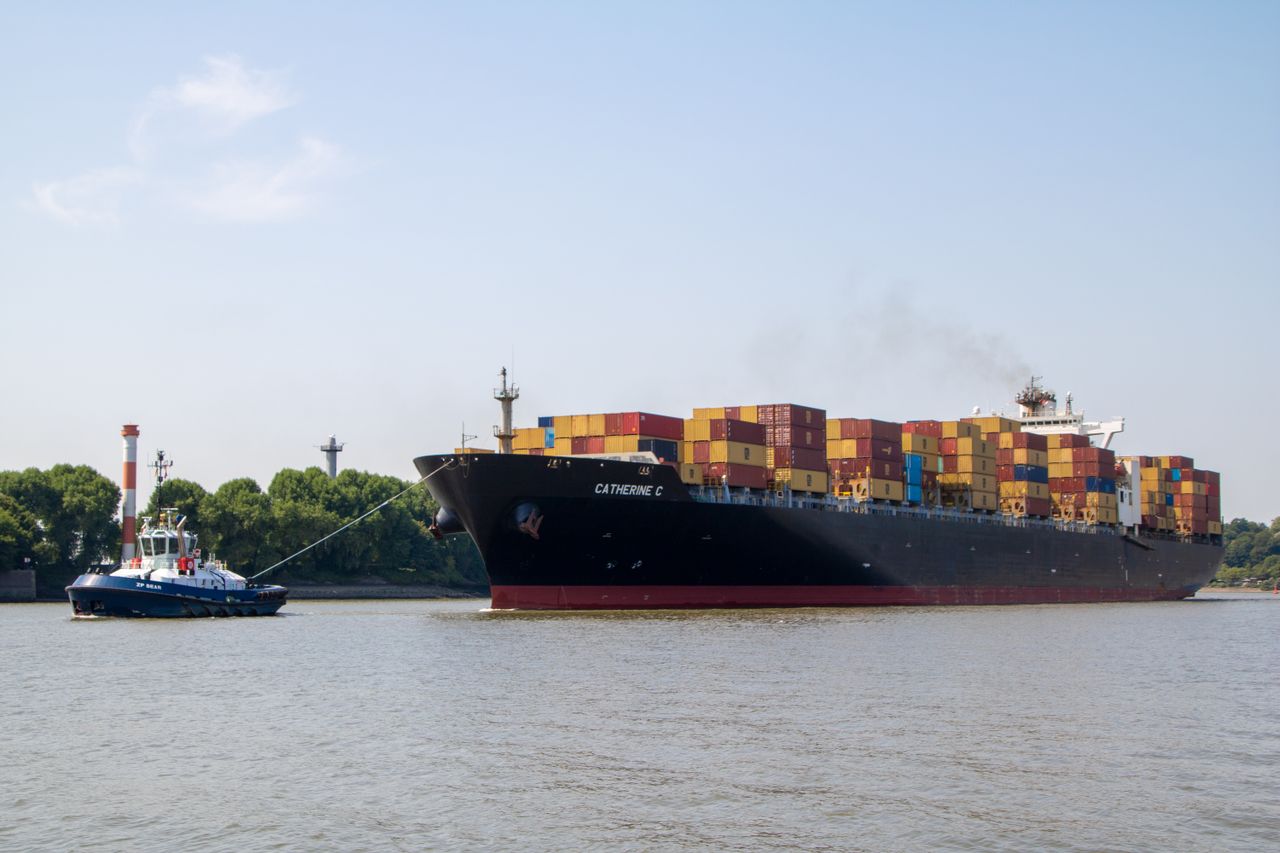 A container ship is guided by a tugboat on the Elbe River in Hamburg, Germany.
