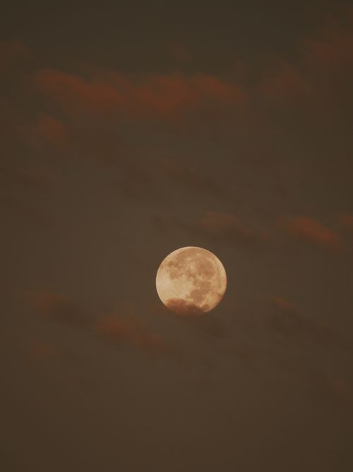 Free A captivating full moon peeks through clouds in a moody night sky, evoking a sense of wonder. Stock Photo