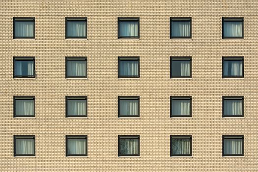 Front view of a yellow brick building with evenly spaced windows, showcasing architectural symmetry.