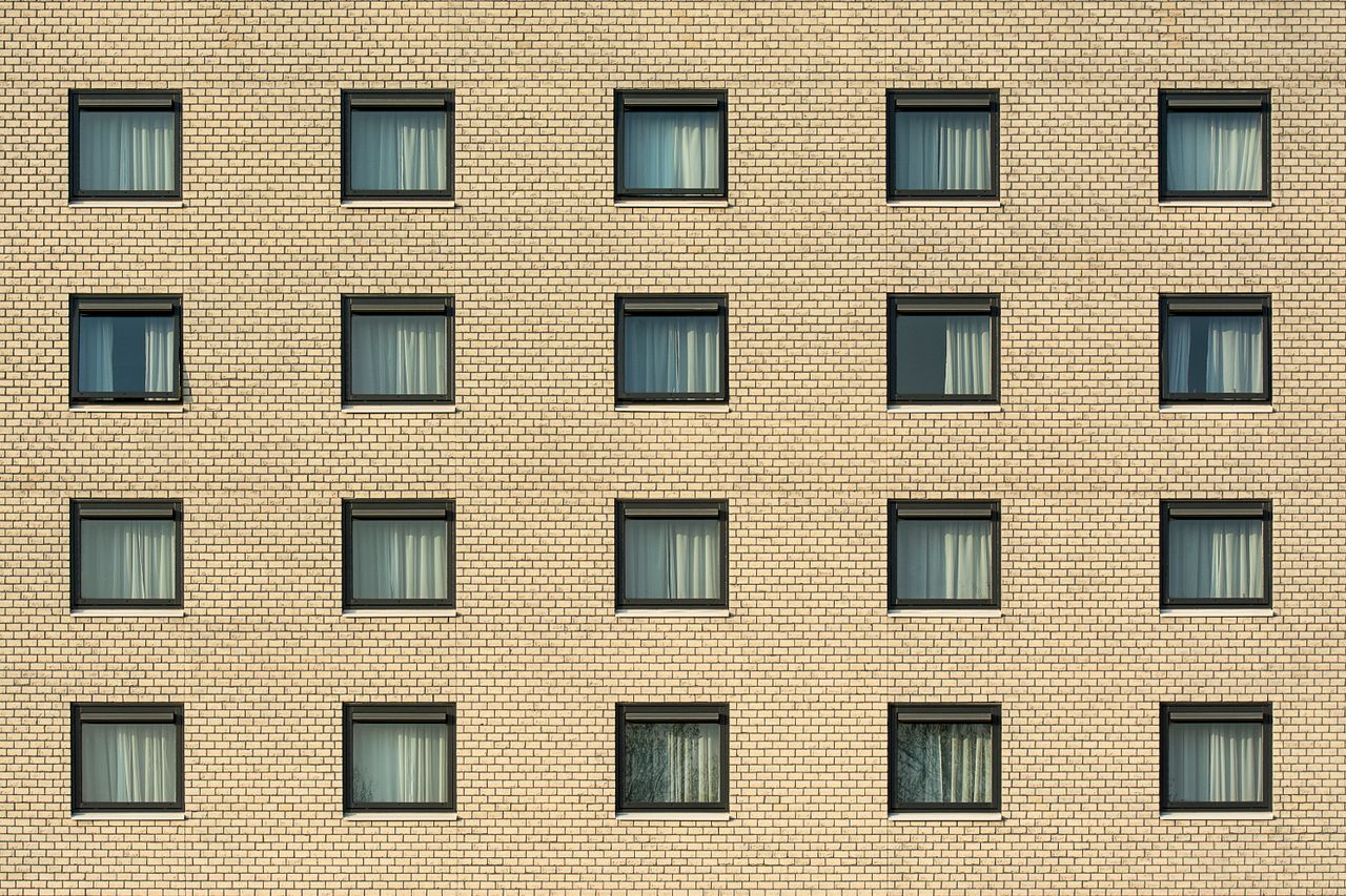 front view of a yellow brick building with evenly spaced windows showc