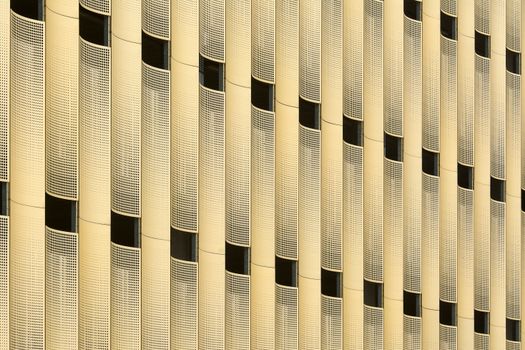 Close-up of a modern building facade with yellow metallic panels creating an urban pattern.