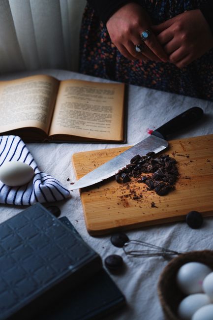 A warm kitchen setting with a cutting board, chocolate, eggs, and an open book.