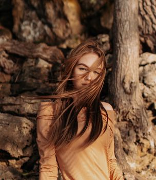 A woman with windswept hair in an outdoor setting, embodying a natural and carefree vibe.