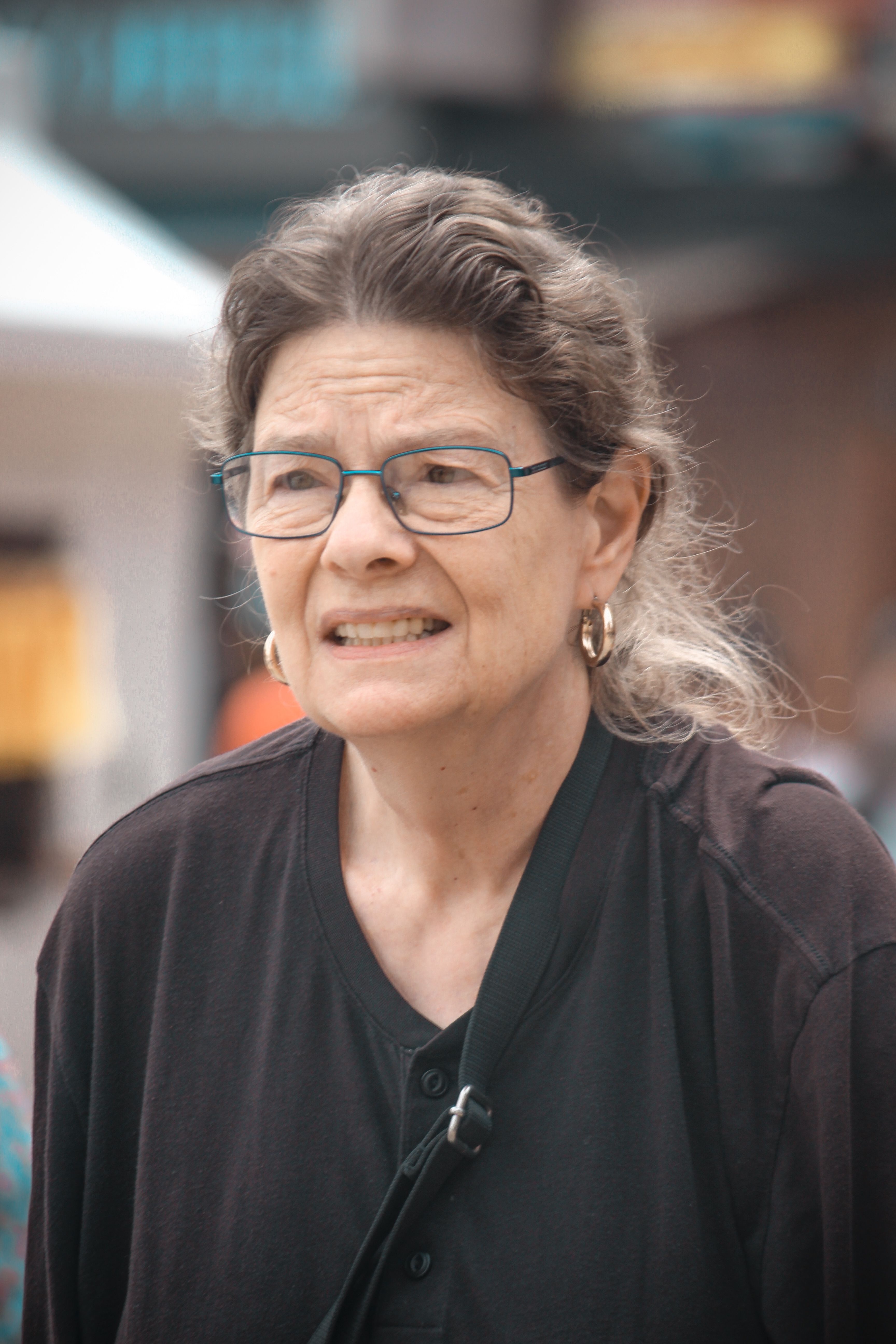 Close-up portrait of a senior woman wearing glasses, captured outdoors with a thoughtful expression.