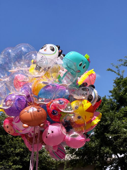 Free Bright and colorful collection of cartoon character balloons floating under a clear blue sky. Stock Photo