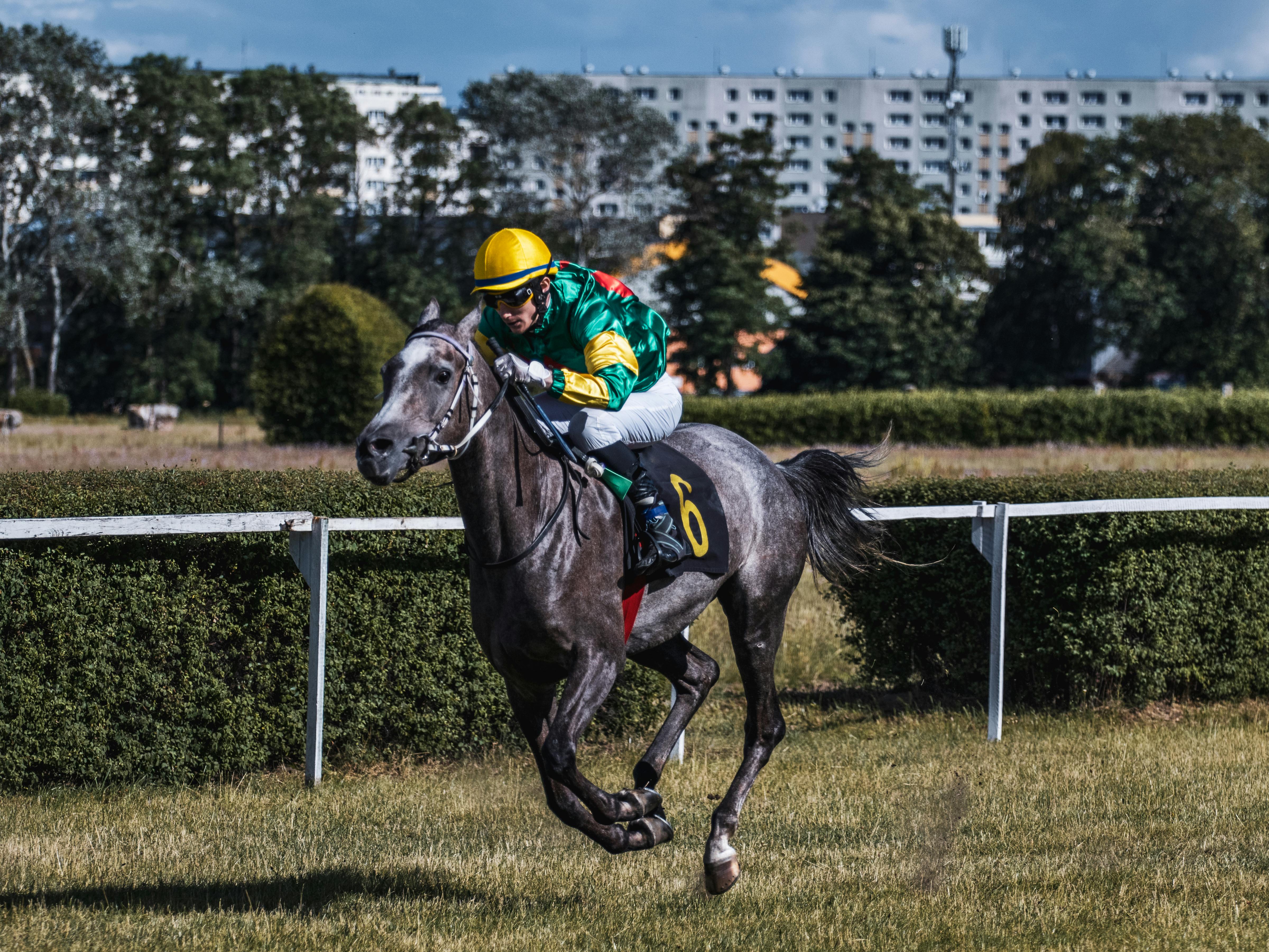 a person in green uniform wearing helmet riding a running horse