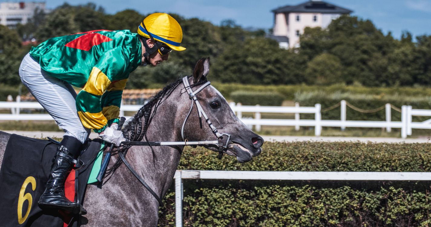 Jockey en pleine action lancé à vive allure sur une piste de course, dans un moment de vitesse intense