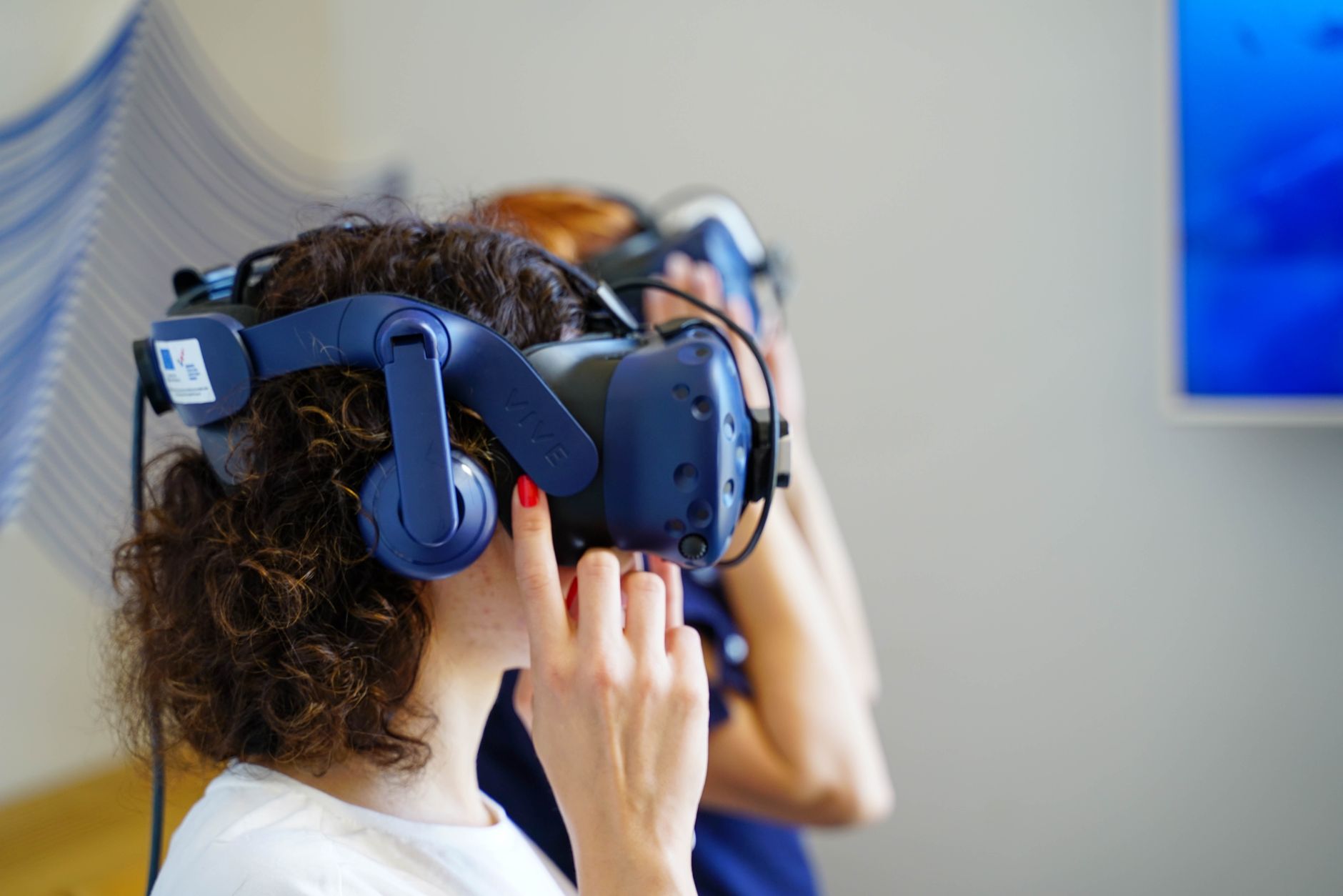 兩位女性配戴 VR 裝置體驗虛擬實境,呈現互動式網頁新趨勢