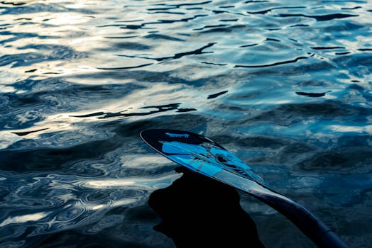 A detailed view of a paddle reflecting on a textured water surface, capturing light patterns.