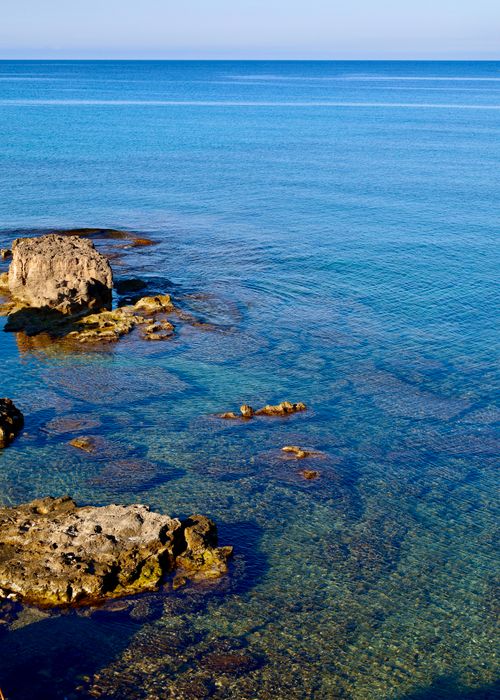 Free Eroded rocks and clear blue sea along the Sardinian coast, showcasing nature's raw beauty. Stock Photo