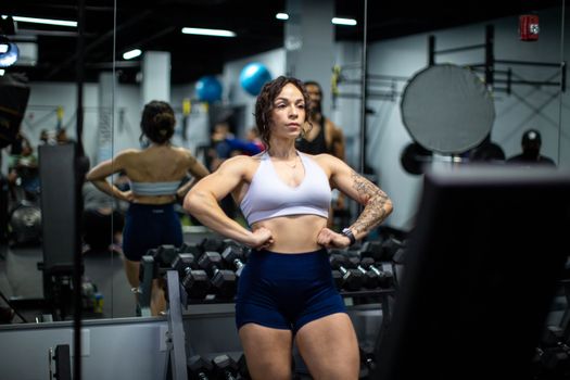 Female athlete in sportswear posing confidently in a gym reflecting in mirrors.