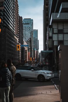 Downtown Toronto street scene with a white SUV and urban pedestrians in winter.