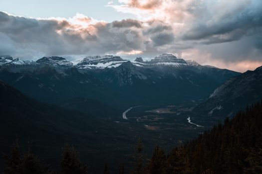 Snow-capped mountains under dramatic sunset clouds, capturing nature's grandeur.