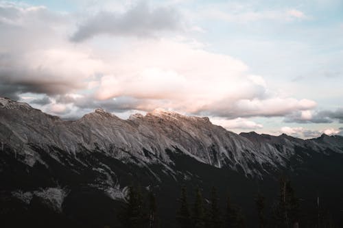 Photo of Snow Capped Mountains Under Cloudy Sky