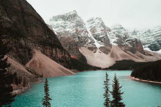 Tranquil turquoise lake surrounded by snowcapped peaks and forested landscape, Alberta.