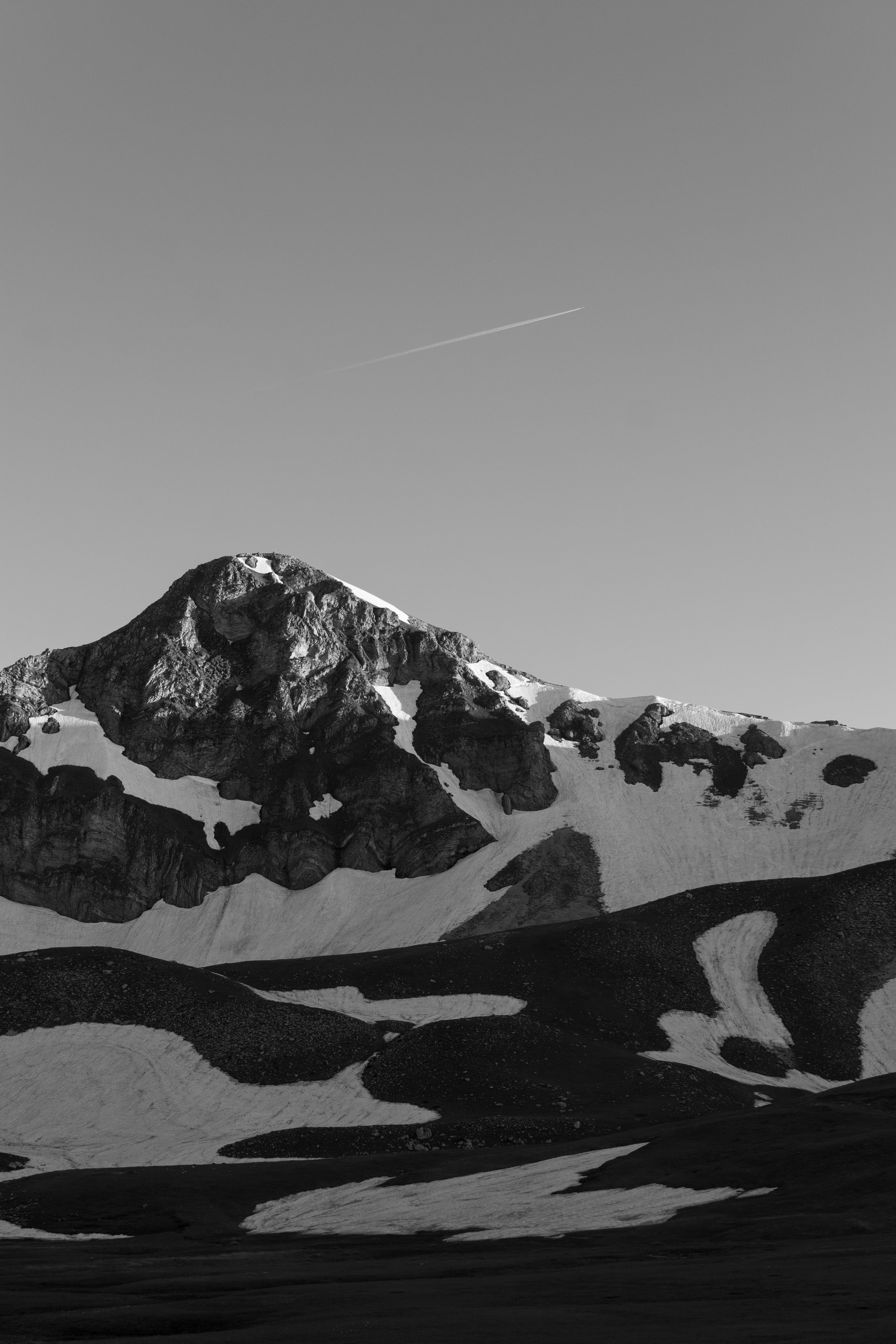 Serene snow-capped mountain captured in grayscale with a dramatic sky.