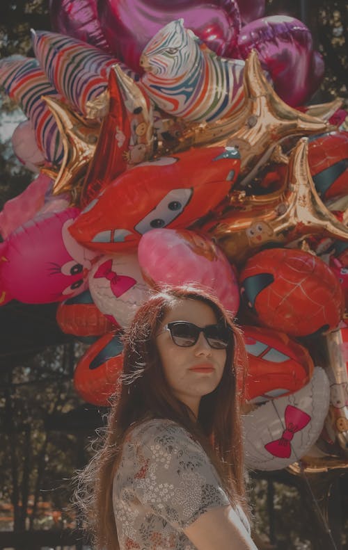 A Woman Wearing Sunglasses Standing near Balloons