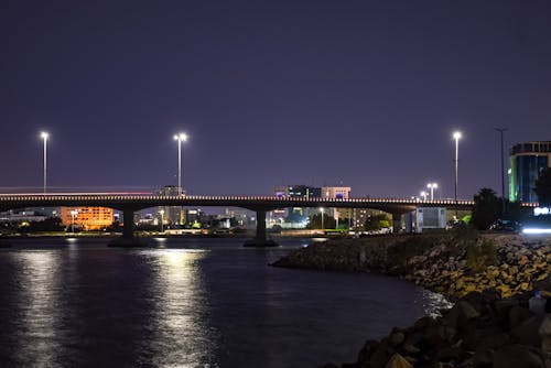 Illuminated Bridge Near the Rocky Coast During Night Time