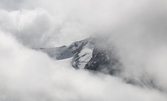 Snow-covered mountains hidden in misty clouds in the Alps, Tirol, Austria.